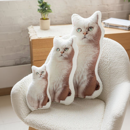 Three custom cat-shaped pillows on a chair with a blurred background