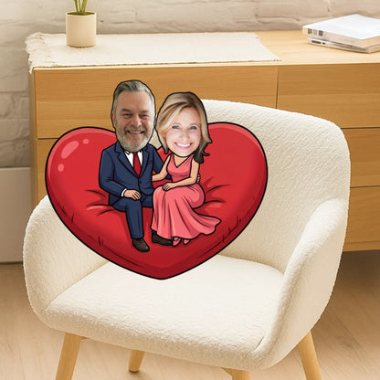 Heart-shaped pillow with cartoon faces of a man and woman on a white chair.