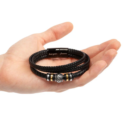 Black braided leather bracelet with metal beads on a hand against a white background