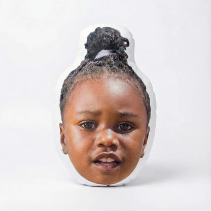 Face pillow of a young child with braided hair on a white background
