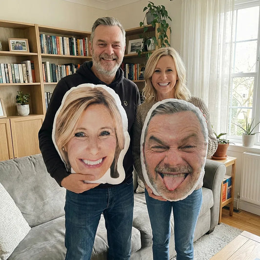 Two people holding custom face pillows of their partners in a living room.