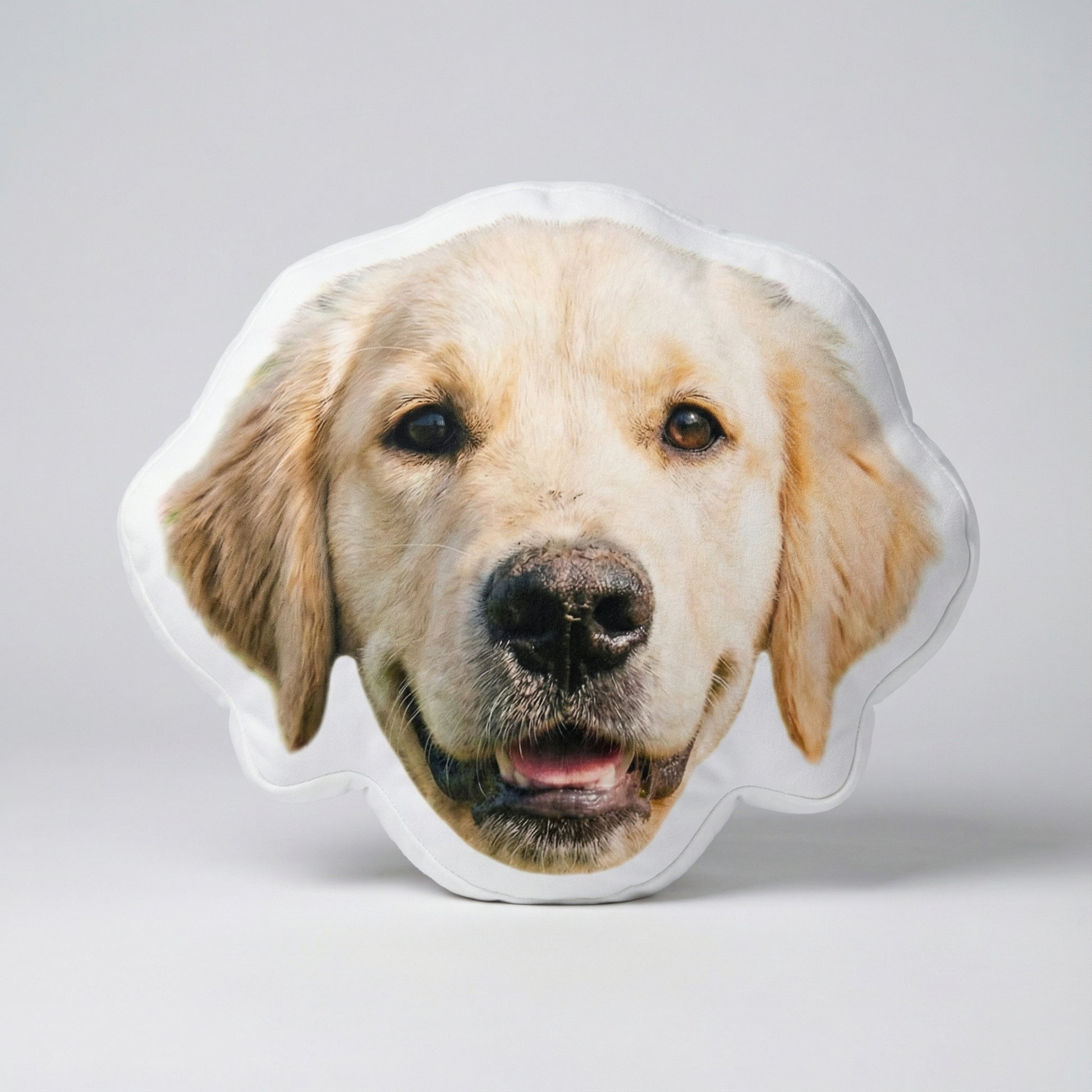 Dog-shaped pillow with a golden retriever face on a light gray background