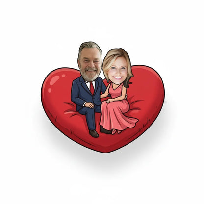 Cartoon caricatures of a man and woman sitting on a red heart-shaped pillow with a white background.